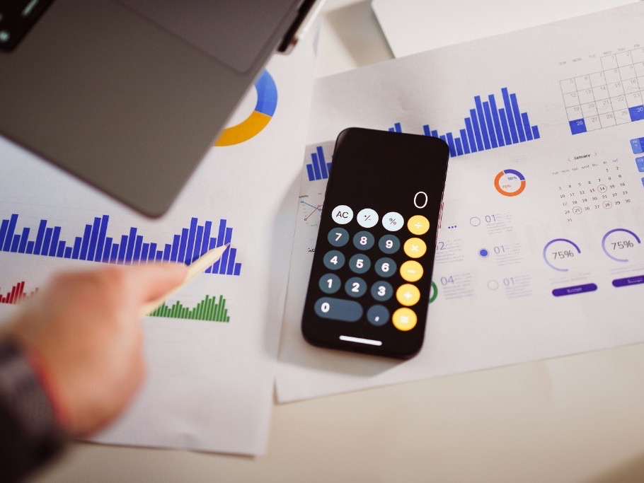 Financial charts and a phone calculator on a desk, representing infrastructure due diligence before investment.
