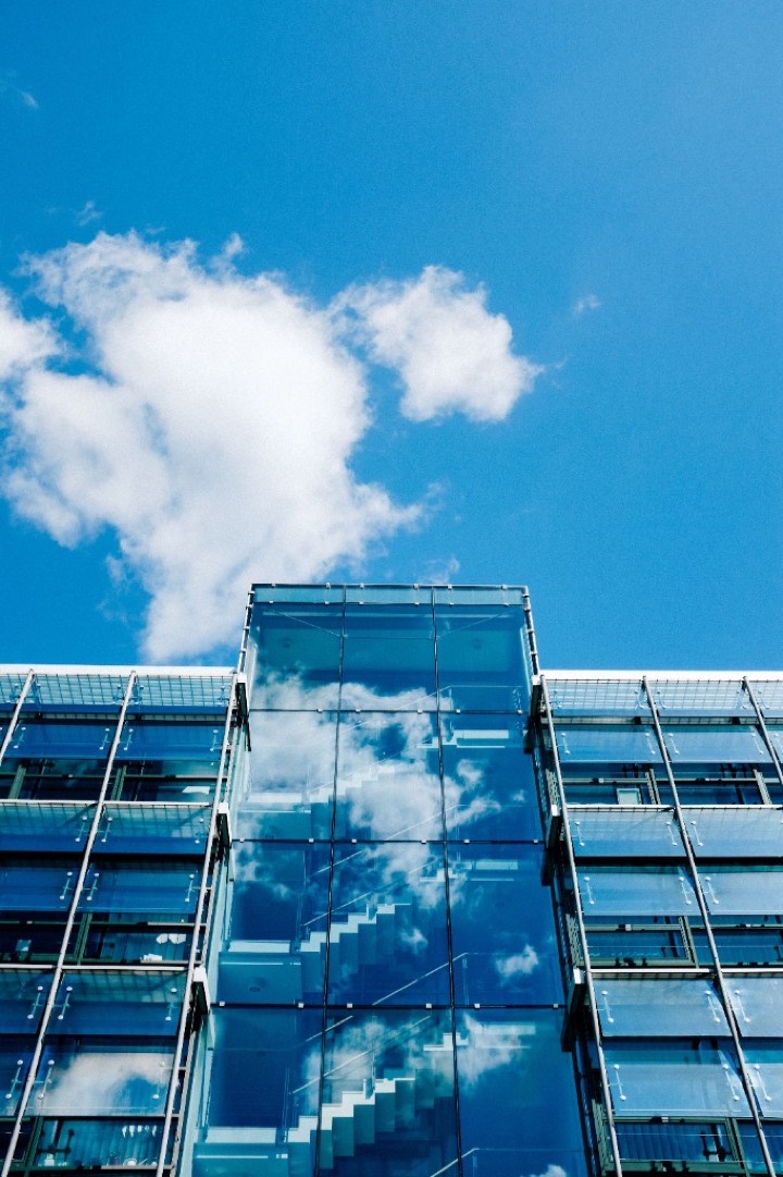 Glass office towers reflecting sky and neighbouring buildings — a dense, layered urban estate.
